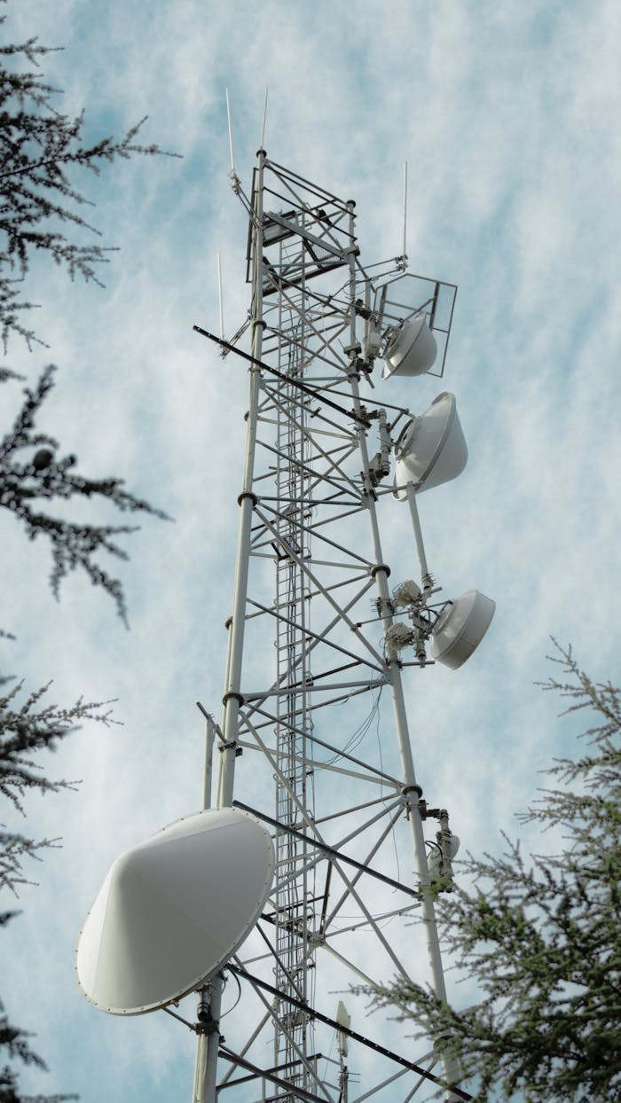Aerial view of a tall telecommunication tower set against a blue sky with clouds.
